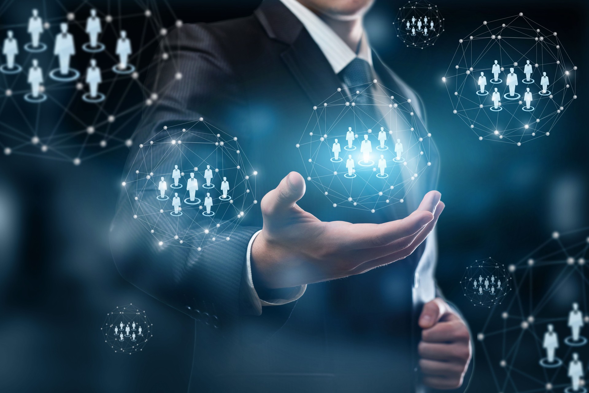 A businessman holding a system of digital spheres with human figures models.